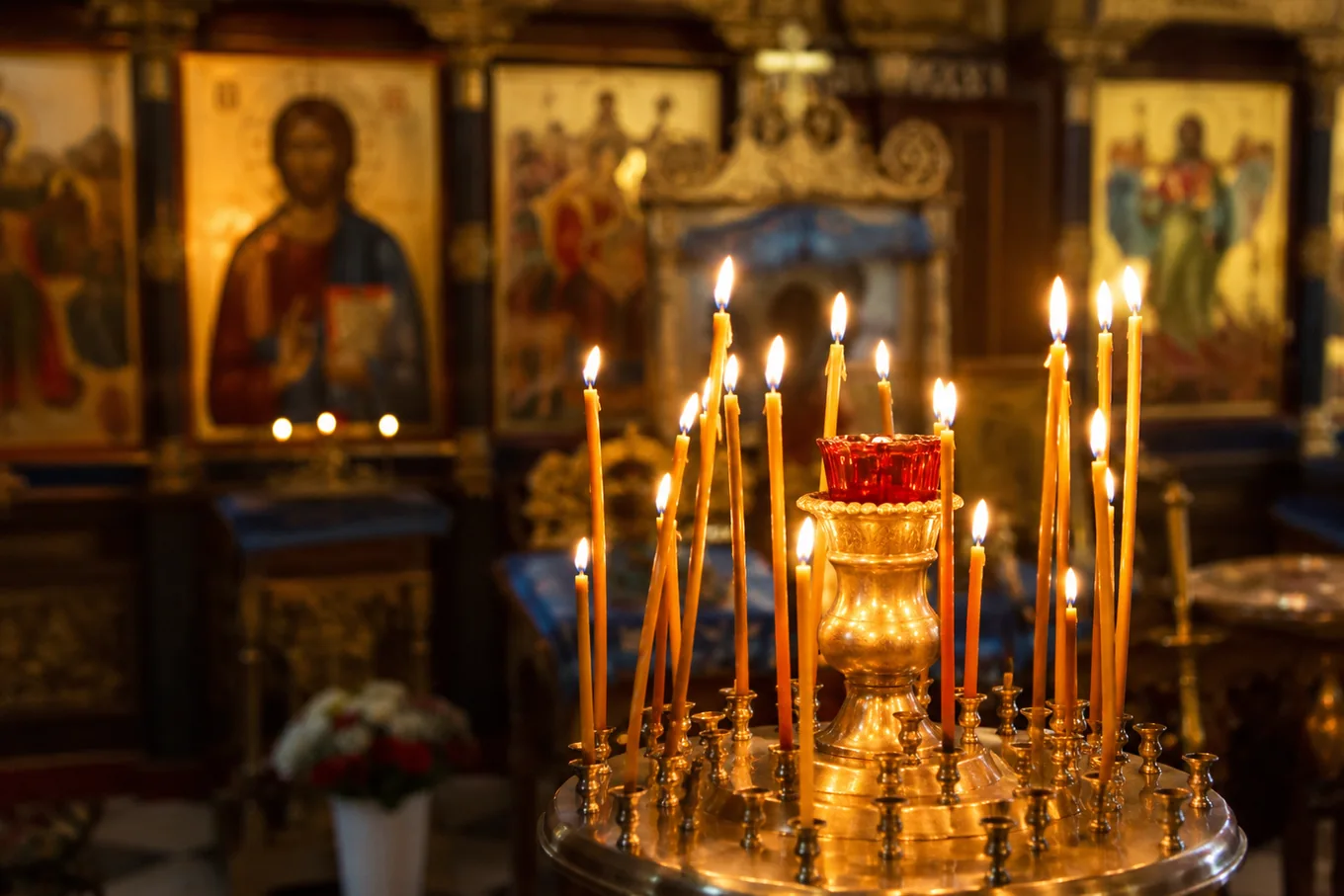 Lumânări aprinse și icoane într-o biserică ortodoxă